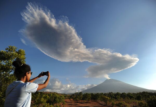 煙が立ち上っているバリ島の アグン山を撮影する女性 - Sputnik 日本