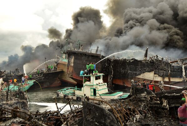 燃え盛る漁船の消火を試みる人々と消防隊。インドネシア - Sputnik 日本