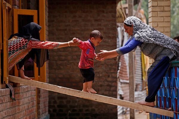 洪水で板を伝って窓から隣の家に移る子どもとそれを助ける女性ら。シュリーナガル - Sputnik 日本
