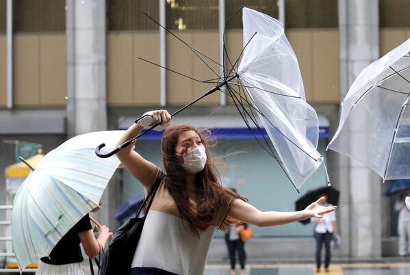 東京で、強風で曲がった傘を直そうとする女性 - Sputnik 日本