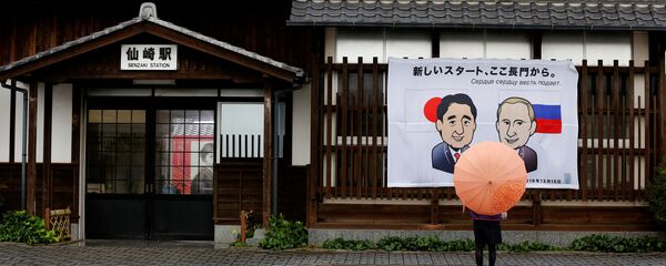 A woman looks at a banner showing Japan's Prime Minister Shinzo Abe and Russian President Vladimir Putin at the Senzaki station in Nagato, Yamaguchi prefecture, Japan, December 14, 2016, a day before their summit meeting. The words on top read, A new start from here in Nagato. - Sputnik 日本