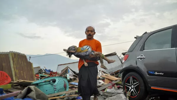 A man carries the body of a child who was killed in the tsunami in Palu, Central Sulawesi, Indonesia - Sputnik 日本