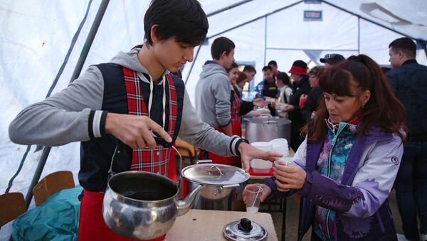 Волонтер разливает горячий чай для пассажиров поезда, задержанных в Краснодарском крае из-за наводнения - Sputnik 日本