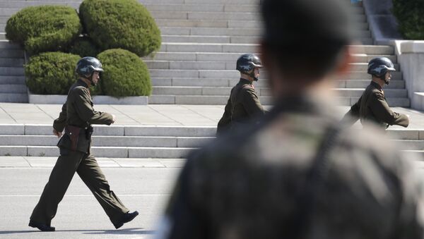 In this April 18, 2018 photo, North Korean soldiers march as a South Korean soldier, center, stands guard during a press tour at the border village of Panmunjom in the Demilitarized Zone, South Korea - Sputnik 日本
