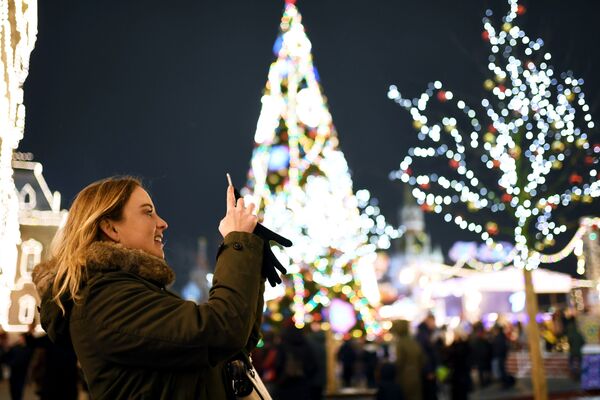 モスクワで、新年を祝う明かりで飾られた赤の広場を写真に撮影する若い女性 - Sputnik 日本