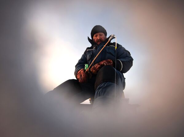 氷に開けられた穴から見える釣り人 - Sputnik 日本