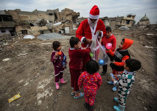 サンタクロースの格好をして子供たちにプレゼントを配る男性、イラクのモスル - Sputnik 日本
