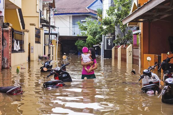 赤ちゃんを手に抱え冠水した道を進む女性。インドネシア - Sputnik 日本
