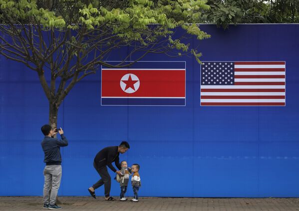 ハノイで米朝首脳会談が開催することを受け描かれた北朝鮮と米国の国旗の絵を前に、ハノイ市民がポーズ - Sputnik 日本
