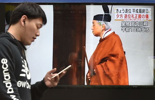 天皇陛下の退位に関するニュースを伝えるスクリーンの近くを通り過ぎる男性 - Sputnik 日本