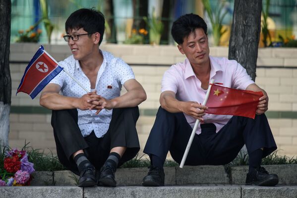 朝鮮民主主義人民共和国と中国の国旗を持つ男性たち　習中国国家主席のピョンヤン訪問時、金日成広場で - Sputnik 日本