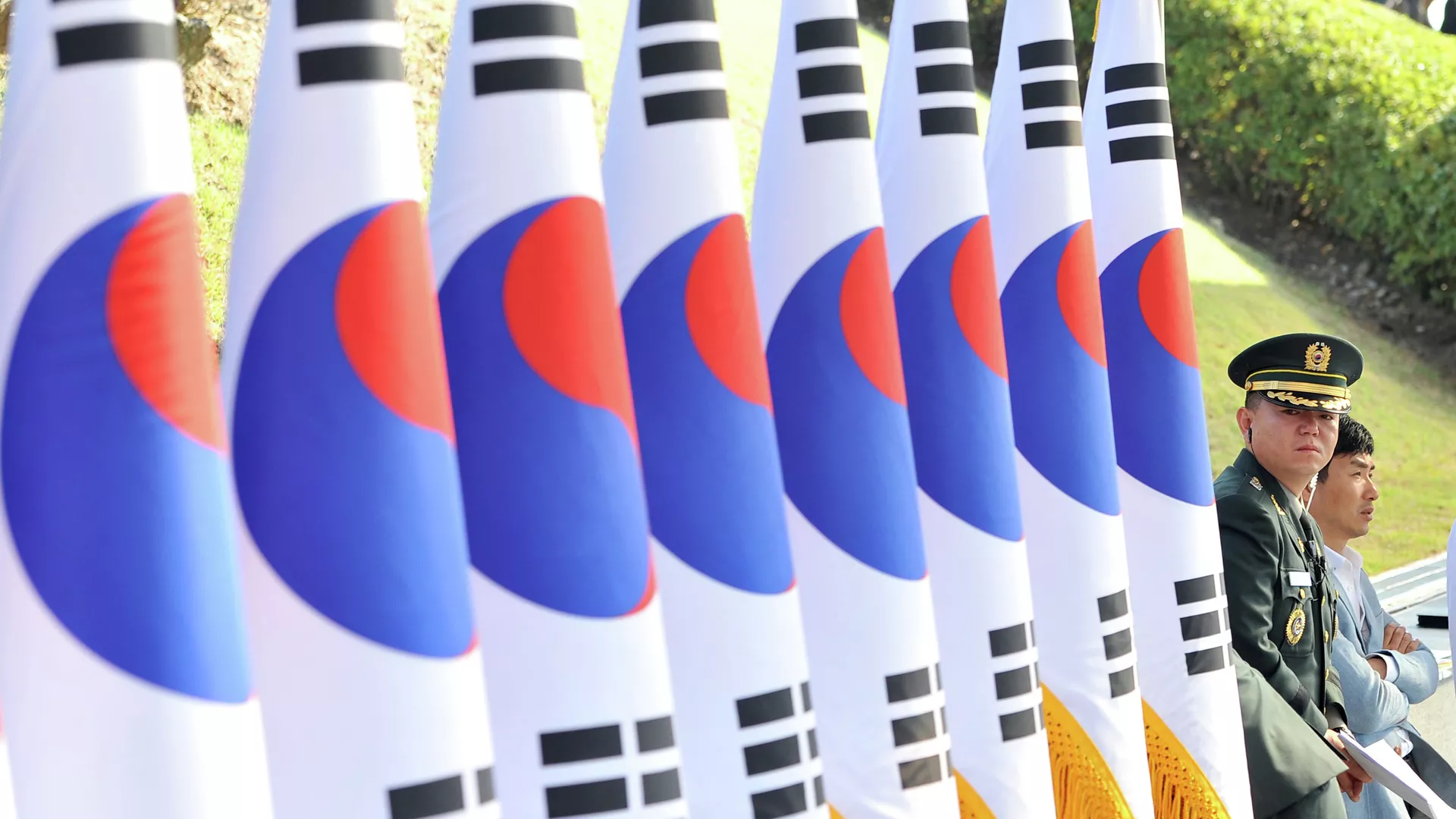 国旗が並ぶ横に立つ韓国軍将校(右)