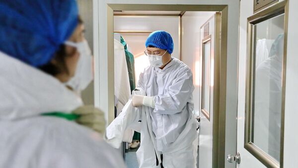 Лабораторный работник надевает защитный костюм перед исследованием образцов в центре по контролю и профилактике заболеваний в Циньхуандао, провинция Хэбэй, Китай - Sputnik 日本