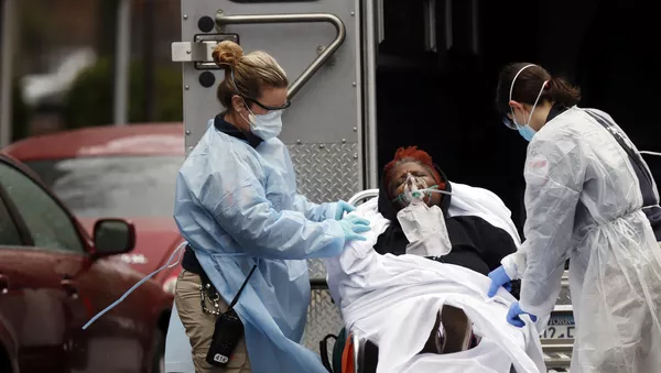 Emergency Medical Technicians (EMT) wearing protective gears wheel a sick patient to a waiting ambulance during the outbreak of coronavirus disease (COVID-19) in New York City, New York, U.S. - Sputnik 日本