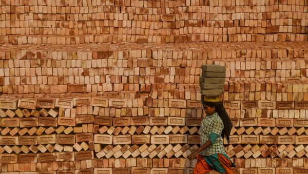 Девушка-мигрантка носит кирпичи на голове во время работы на заводе по производству кирпичей на окраине Калькутты, Индия - Sputnik 日本