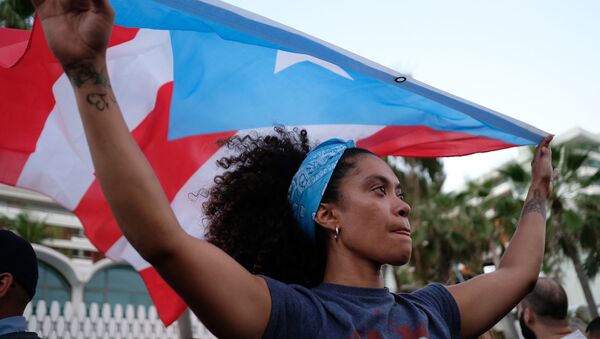 プエルトリコの国旗を掲げる女性
 - Sputnik 日本