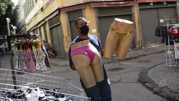 Продавец в защитной маске переносит манекены на уличном рынке в Рио-де-Жанейро - Sputnik 日本