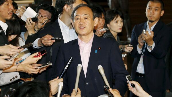 Japan's Chief Cabinet Secretary Yoshihide Suga (C) is surrounded by reporters as he holds an emergency news conference following the eruption of a volcano in southern Japan, at prime minister Shinzo Abe's official residence in Tokyo, in this photo taken by Kyodo May 29, 2015 - Sputnik 日本