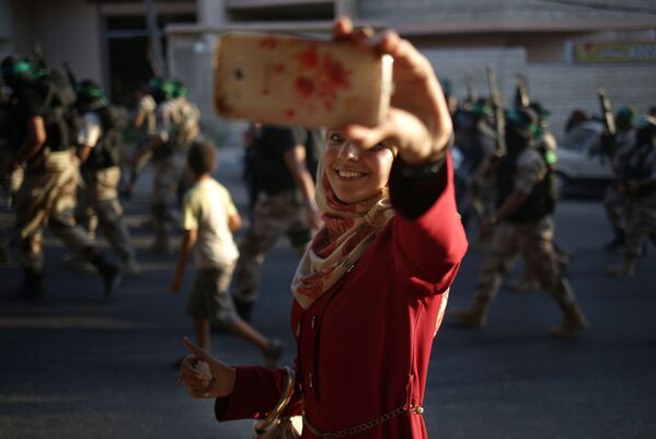ハマスの軍事パレードで自分を写すパレスチナ女性。 - Sputnik 日本